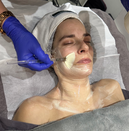 facial hertfordshire - a woman laying on a bed having a facial treatment.